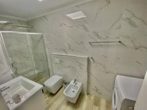 Baño blanco con lavabo y aseo en Central Apartment Blloku, en Tirana
