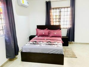 ein Schlafzimmer mit einem Bett mit rosa Kissen darauf in der Unterkunft Wyndham Villa in Ogbojo