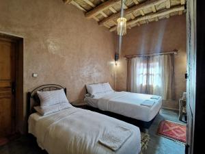 1 Schlafzimmer mit 2 Betten und einem Fenster in der Unterkunft Maison d'hôte tamatart - Homestay in El-Kelâa M’Gouna