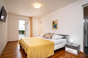 a bedroom with a bed with a yellow blanket on it at Spacious modern One bedroom Apartment with Garden & SeaView in Rab