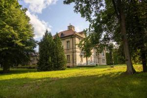 an old house on a grassy field with trees at Palac Czerniejewo in Czerniejewo +54 photos