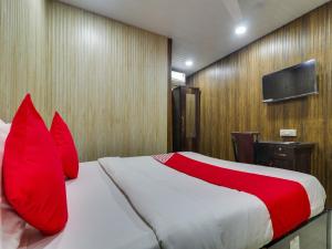 sypialnia z łóżkiem z czerwonymi poduszkami i telewizorem w obiekcie Super OYO Flagship Hotel Diamond w Bombaju