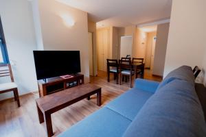 a living room with a blue couch and a tv at Pierre & Vacances La Merceria in El Tarter