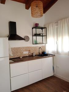 eine Küche mit weißen Schränken und einem Waschbecken in der Unterkunft Casita independiente con jardin in Cercedilla