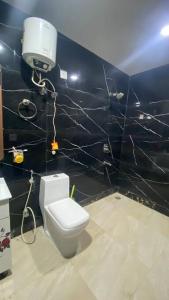 a bathroom with a white toilet and a black wall at Moksha Farm, 3BHK Luxury Farm Stay, 7000 sq ft in Noida