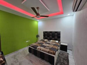 a bedroom with green walls and a bed with a ceiling fan at Moksha Farm, 3BHK Luxury Farm Stay, 7000 sq ft in Noida