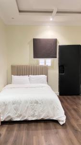 1 dormitorio con 1 cama blanca grande y TV en la pared en استيديو بالعقيق بدخول ذاتي c3 en Riad