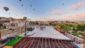 a balcony with a table and chairs and hot air balloons at Atax Cave House in Avanos