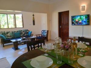 a dining room with a table and a living room at Tahira Villa in Diani Beach