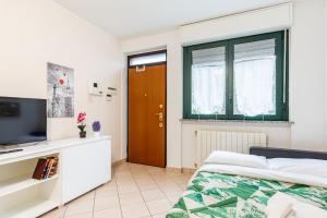 een slaapkamer met een bed en een televisie en een deur bij Accogliente Bilocale con Giardino e Parcheggio in Monza