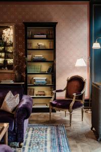 a living room with a chair and a book shelf at Grand Hotel LES TROIS ROIS in Basel