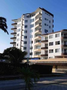 a large white building with palm trees in front of it at Hermoso departamento, excelente vista al mar in Tonsupa