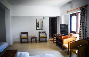 a living room with a tv and a desk and chairs at Dragon I Resorts in McLeod Ganj