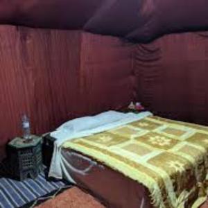 a bed in a room with a wooden wall at Ibra desert Camp in Merzouga