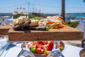 un plato de comida en una mesa con una ensalada en Luxurious Santorini Masionette Villa - 1 Bedroom - Astounding Caldera Sea Views and Private Outdoor Hot Tub - Fira en Fira