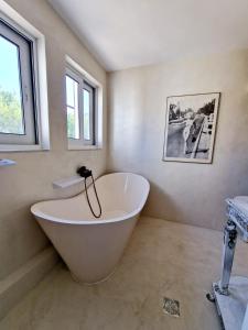 eine große weiße Badewanne im Bad mit Fenstern in der Unterkunft Luxurious studio apartment close to the beach and airport in Porto Rafti