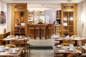 a restaurant with tables and chairs and a kitchen at Hotel Christophe Colomb in Luxembourg