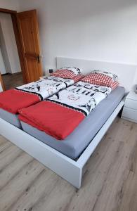 uma cama com cobertores e almofadas vermelhos e brancos em Ruheort em Beinwil