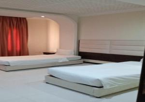 a bedroom with two beds and a red curtain at فندق سما اشبيليه الرياض in Riyadh