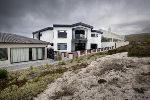 ein weißes Haus mit einem Zaun davor in der Unterkunft Yzerfontein Beach Accommodation in Yzerfontein