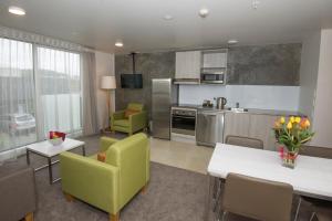 eine Küche und ein Wohnzimmer mit grünen Stühlen und Tischen in der Unterkunft Quest Nelson in Nelson