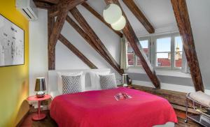 プラハにある4 Arts Apartments by Adrezの木製の梁があるベッドルームで、赤いベッドが備わります。