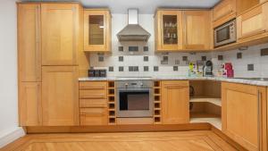 cocina con armarios de madera y fogones en The Lodge - Exquisite 2 Bed with Ensuite en Birmingham