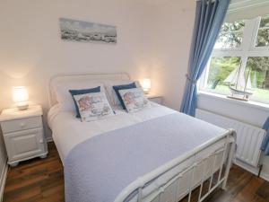 - une chambre dotée d'un lit blanc avec des rideaux bleus et une fenêtre dans l'établissement Gortin Cottage, à Ballymena
