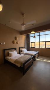 a bedroom with two beds and a large window at Sand House ساند هاوس in Al Raka