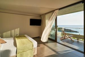 a bedroom with a bed and a view of the ocean at White Rocks Hotel Kefalonia in Lassi