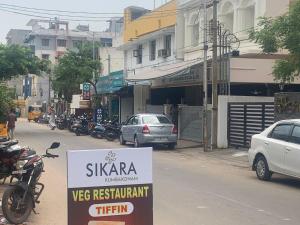 a sign on the side of a city street with cars at Hotel Sikara, Kumbakonam in Kumbakonam