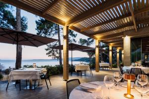 un restaurante con mesas, sillas y sombrillas en White Rocks Hotel Kefalonia en Lassi