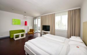 a bedroom with a large white bed and a green chair at Stanys - Das Apartmenthotel in Vienna