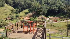 a wooden deck with two chairs and a table on it at Chalé monte verde com hidromassagem in Camanducaia