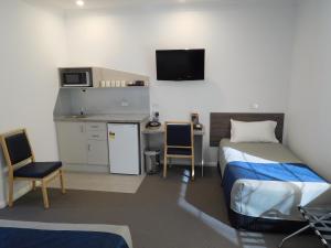 a room with a bed, a desk and a television at Commercial Golf Resort in Albury