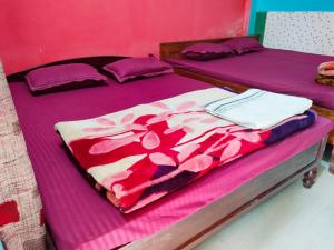 two beds in a room with purple and pink sheets at Hotel Green Gold Resort Lataguri in Lataguri