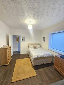 a bedroom with a bed and a dresser and a window at The perfect location when working in Swansea! in Swansea