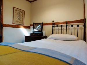 a bedroom with a bed and a tv on a table at Gallestra a Rustic, Rural Retreat Farm House Nr Dolgellau Snowdonia in Dolgellau