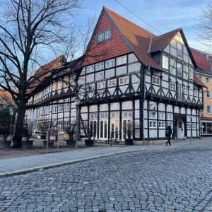 a large building with a red roof on a cobblestone street at Magni Boutique Hotel in Braunschweig