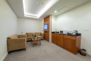 Sala de espera con 2 sillas, mesa y TV en فندق روز جدة 2 en Yeda