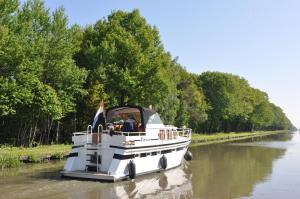 a white boat traveling down a river at Camping Het Veen in Brecht