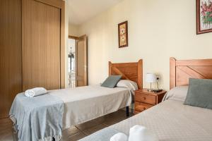 a bedroom with two beds and a dresser with a lamp at Apartamento familiar muy soleado cerca de la playa y parking incluido in Chiclana de la Frontera +32 photos