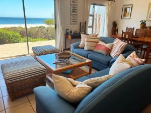 una sala de estar con sofás azules y vistas al océano. en Beach Haven Cottage, en Britannia Bay