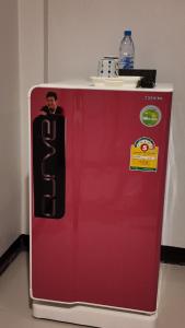 Un refrigerador rojo con un hombre dentro. en กัญญ่า เพลส KANYA, en Maha Sarakham