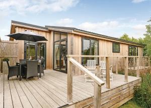 a house with a deck with a table and an umbrella at Weybread Lakes Lodges in Brockdish
