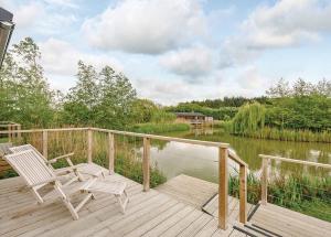 a deck with two chairs and a view of a lake at Weybread Lakes Lodges in Brockdish