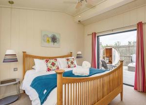 a bedroom with a large bed and a balcony at Weybread Lakes Lodges in Brockdish