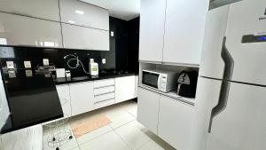 cocina con armarios blancos y microondas en EDF SEVILHA - Apartamento com 1 suíte climatizada e 2 Banheiros, Sala Climatizada a 300 metros da Beira-Mar de Ponta Verde - EXCELENTE LOCALIZAÇÃO, en Maceió