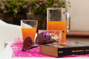 um par de óculos de sol e um copo de sumo de laranja em BeB Scarabeo Milazzo em Milazzo