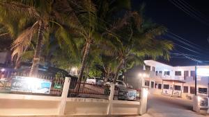 una valla frente a una casa con palmeras en กัญญ่า เพลส KANYA en Maha Sarakham